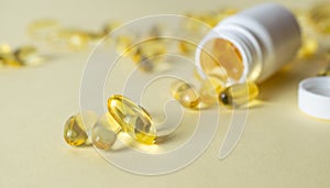 Soft gels pills with Omega-3 oil spilling out of pill bottle close-up on a yellow background. Medical prescription