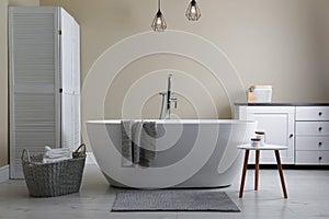 Soft grey mat on floor near tub in bathroom. Interior design