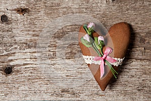 Soft heart made of cloth with pink roses on a wooden background