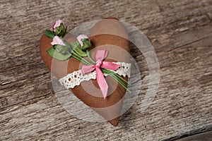 Soft heart made of cloth with pink roses on a wooden background