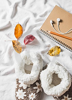 Soft home uggs, notepad, headphones, autumn leaves - lazy cozy home weekend. On a light background