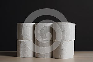 Soft, hygienic white toilet paper on black background, wood table
