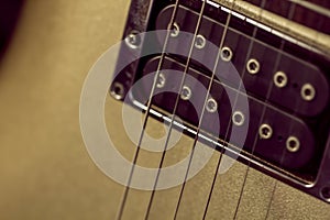 Soft image of a black humbucking pickup on a gold guitar