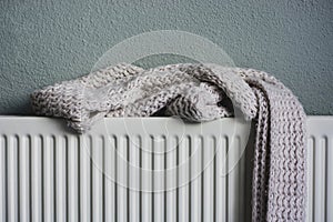 Soft knitted pink scarf drying on a heating radiator after getting wet