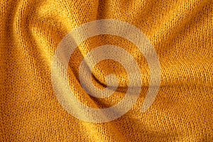 Soft knitted yellow sweater texture closeup. Light orange abstract background