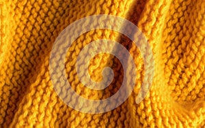 Soft knitted yellow sweater texture closeup. Light orange abstract background