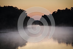 Soft mist hovering over river winding through wilderness, sky an