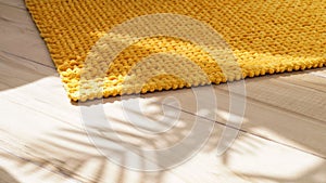 Soft mustard color bath mat on wooden floor indoors, closeup