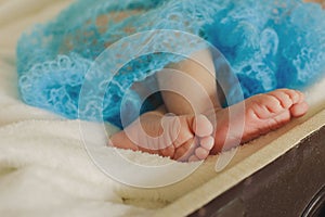 Soft newborn baby feet against a blue blanket.