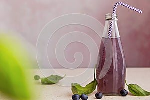 Soft organic purple cocktail bottle with blueberries, seeds, basil extract, leaves. Refreshing healthy Asian drink