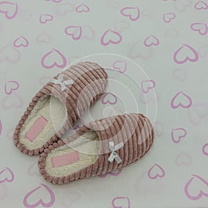 Soft pink plush indoor slippers decorated with bows