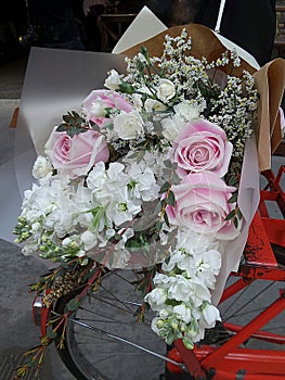 Soft pink roses and white flowers bouquet on red bicycle