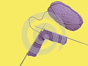 purple ball of yarn and knitting needles on a yellow background, space to insert text