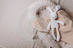 Soft rabbit toy on beige cocoon, baby nest for newborn over cribs in nursery. Childhood concept. Eco-friendly safe