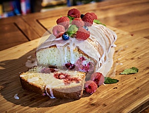 Soft raspberry fruitcake or cake with sweet melted sugarcoat and wild raspberries on wooden table. Sugarcoated, soft warm plumcake photo