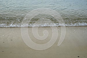 Soft sandy beach with fresh sea water and white foamy wave background and copyspace on Ornos shore