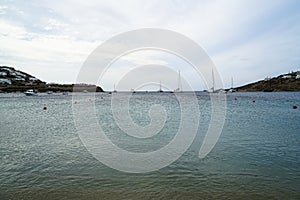 Soft scenic beautiful seascape with sailing boats, yachts, clear sky, mountain and white building background, Ornos beach