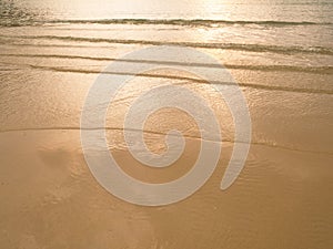 Soft sea wave sand beach at sunset / sunrise. Orange color of sea water surface reflect with sunset. Summer an recreation concept