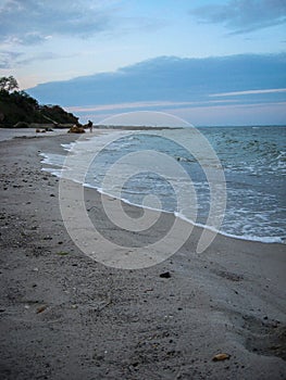 The soft sea waves gently roll on the sandy beach. Beautiful picture of dawn on the seashore