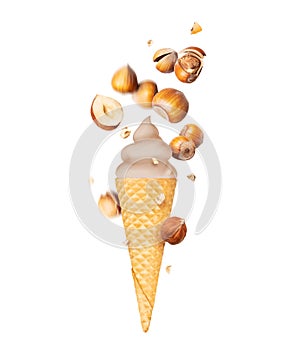 Soft serve ice cream with hazelnuts in wafer cone close-up, isolated on white background