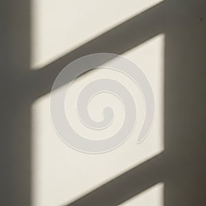 Soft shadows of a window frame create geometric patterns on a beige wall. The light and shadow form