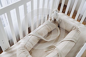 Soft sheep toy on beige cocoon, baby nest for newborn over cribs in nursery. Childhood concept. Eco-friendly safe