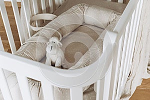 Soft sheep toy on beige cocoon, baby nest for newborn over cribs in nursery. Childhood concept. Eco-friendly safe