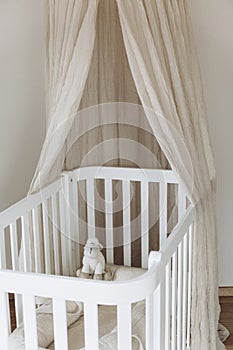 Soft sheep toy on beige cocoon, baby nest for newborn over cribs in nursery. Childhood concept. Eco-friendly safe