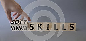 Soft Skills and Hard Skills symbol. Hand turns a cube and changes the words Soft Skills to Hard Skills. Beautiful grey background