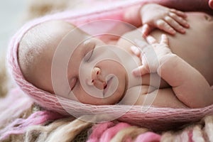 Soft sleeper newborn girl in pink on beige wool