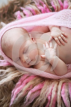 Soft sleeper newborn girl in pink on beige wool