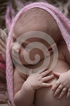 Soft sleeper newborn girl in pink on beige wool