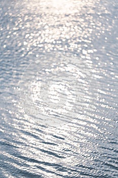 Soft and smooth water wave ripple with blurred bright abstract bokeh of sun light.