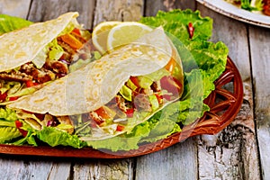 Soft tortillas stuffed with lettuce, meat and cheese on wooden background. Mexican food concept