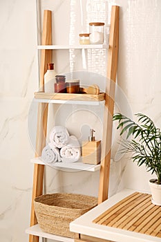 Soft towels and different toiletries on decorative ladder in bathroom. Interior design