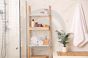 Soft towels and different toiletries on decorative ladder in bathroom. Interior design