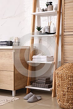 Soft towels and different toiletries on decorative ladder in bathroom. Interior design