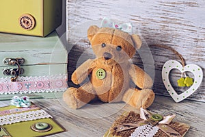 Soft toy bear girl with a bow. Toy on a wooden table with a box and a heart