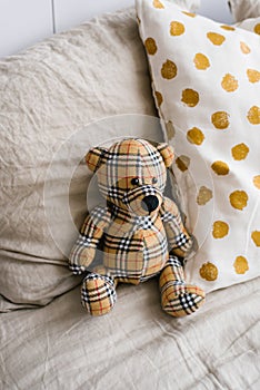 Soft toy bear made of plaid fabric surrounded