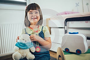 Soft toy bear with protective medical mask in child hands.