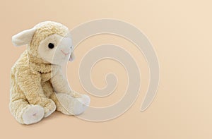 The soft toy little sheep sits on a bright background