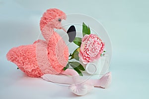 Soft toy pink flamingo with peony flower isolated on the white background.