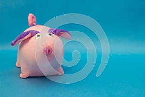 Soft toy pink pig with big ears on a blue background, close-up, the new year of the pig, swine, copy space, satisfied