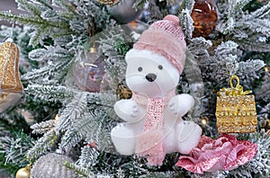 Soft toy polar bear cub in a knitted hat and scarf on the Christmas tree.