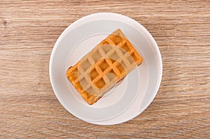 Soft wafer with stuffed in white saucer on wooden table