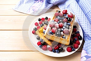 Soft waffle with blueberry and raspberry on blue linen napkin