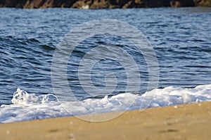 Soft wave hitting sandy beach under bright sunny day