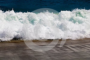 Soft wave of the sea on the sand beach with sunlight. Tropical sandy beach background with copy space. Top down view