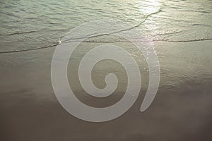 Soft wave of the sea on sandy beach sunset