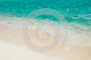 Soft wave of the turquoise sea on the sandy beach. Natural summer background with copy space. Playa Del Carmen, Mexico.